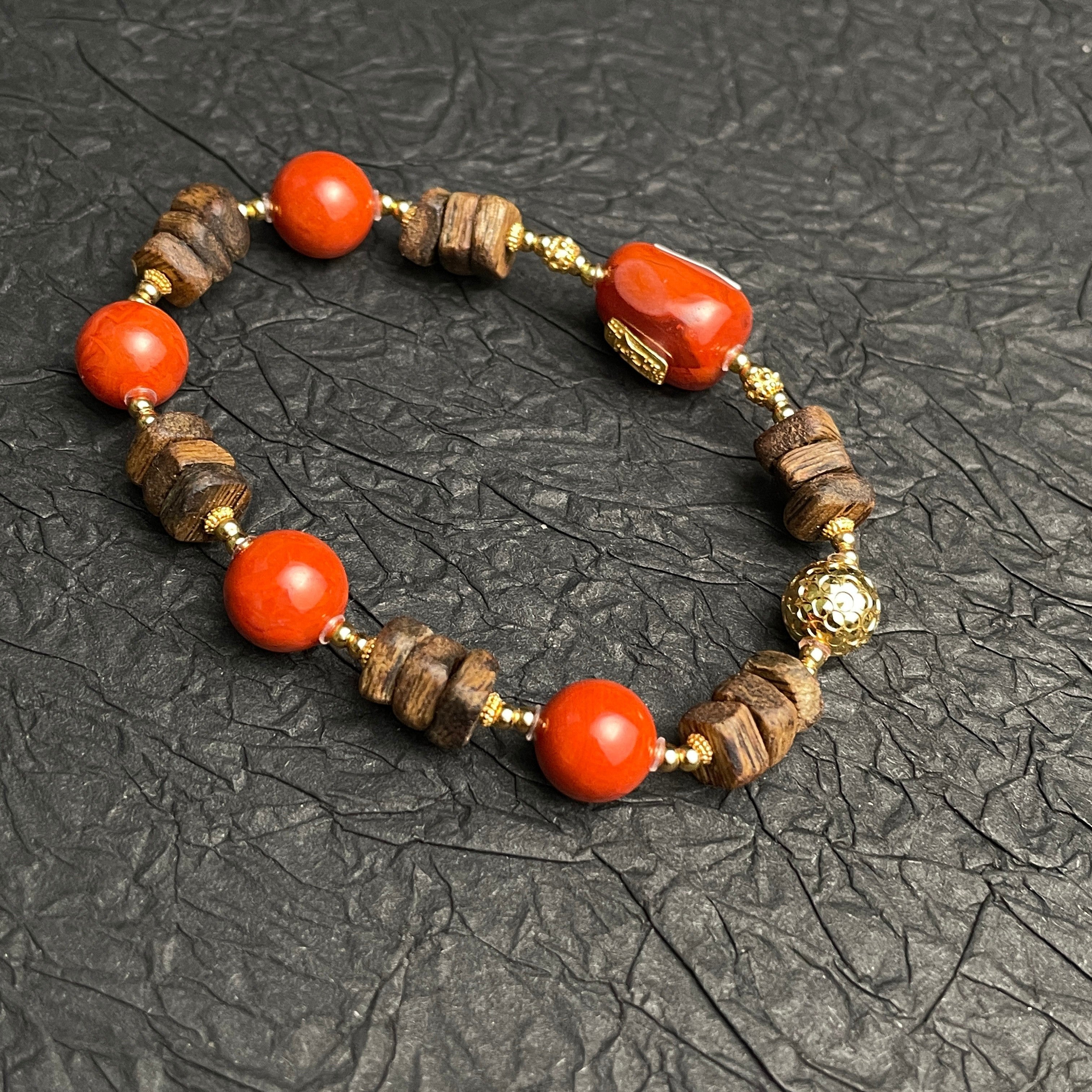 Sylvia Jewelry Nanhong Agate and Agarwood beaded bracelet with gold accents. Features vibrant red agate beads and natural wood beads.